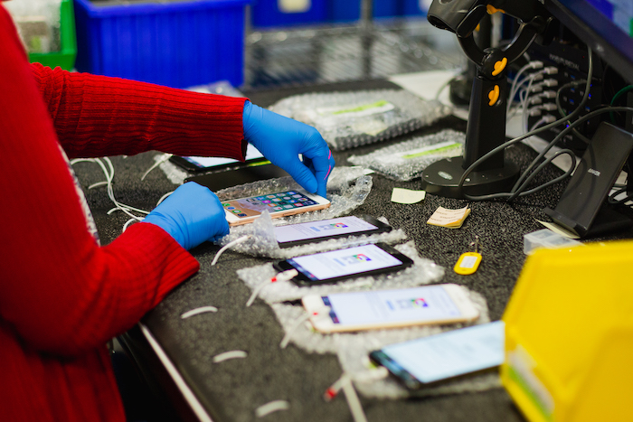 Row of mobile phones being fixed by an individual wearing a red sweater