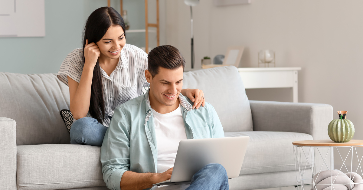 a woman and a boy sitting on a couch looking at a laptop