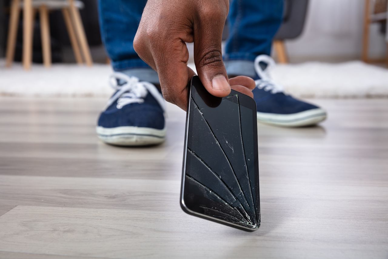 Man's hand picking up a broken mobile device