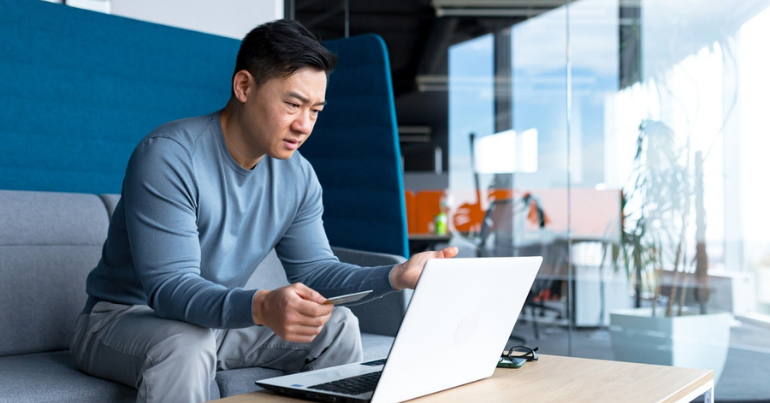 man sitting on couch frustrated at laptop