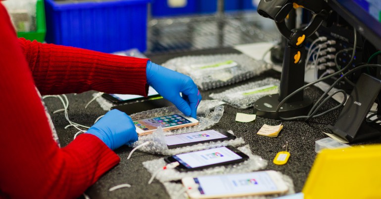 hands working on mobile devices at Assurant depot