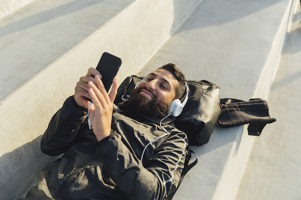 a person lying on the ground with headphones on and a cell phone