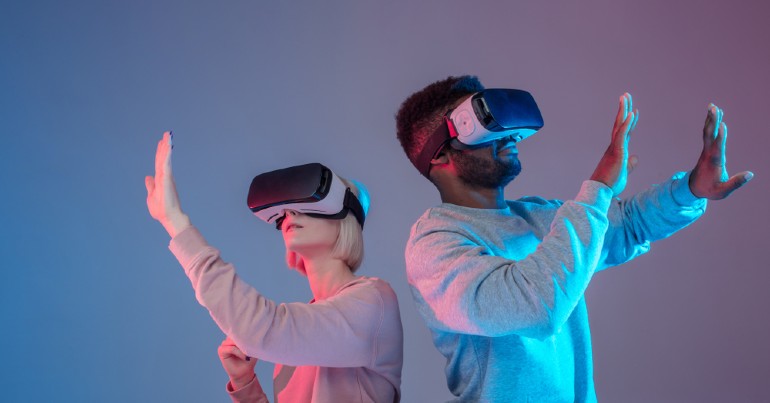 man and woman with virtual reality headsets on reaching in the air