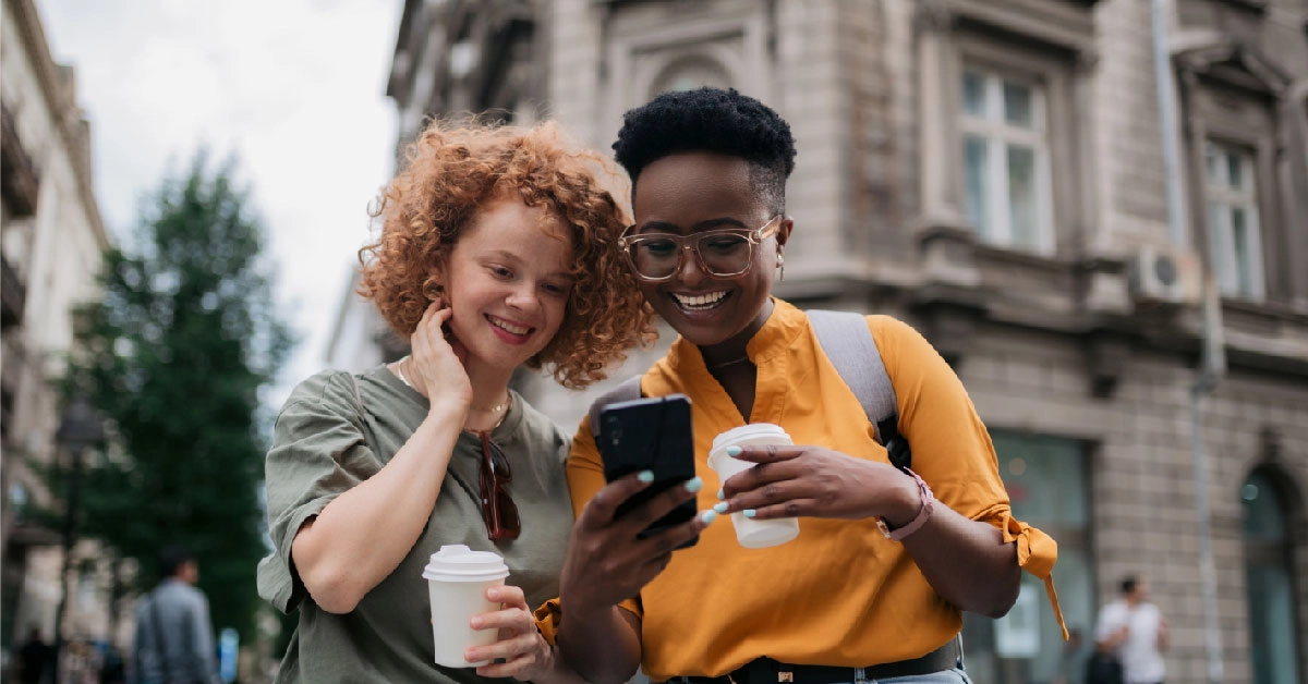 two women looking at phone on outside