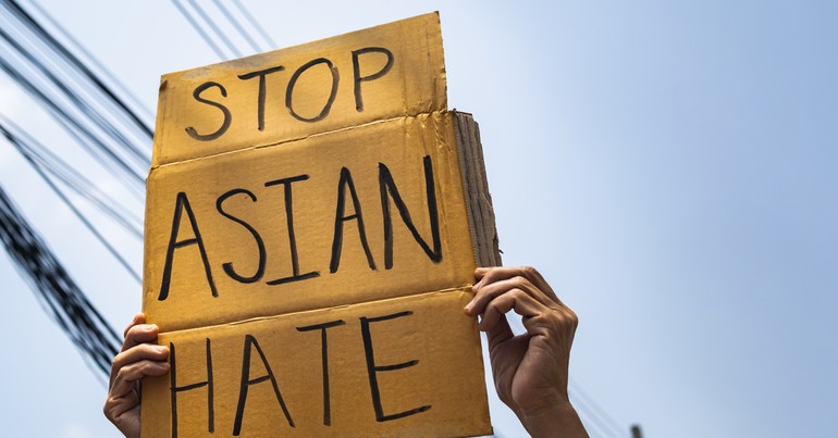 Person holding protest sign that says "STOP ASIAN HATE"