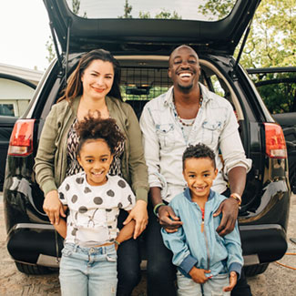 a group of people posing for a photo in front of a car