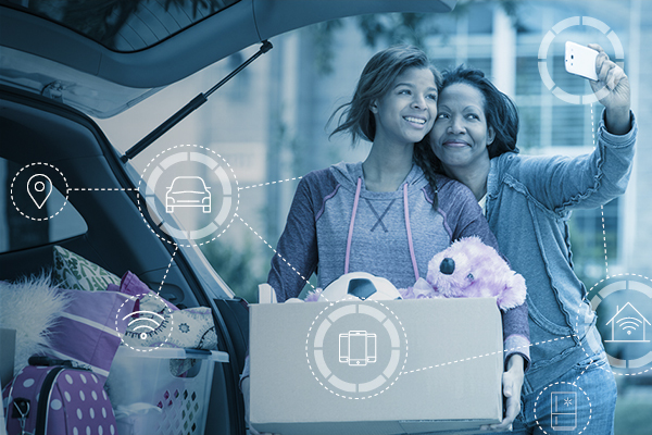 Teenage daughter smiling and carrying a box of toys while mother takes a selfie of them both