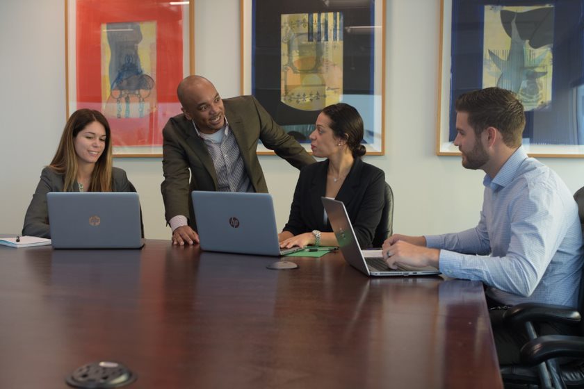 Group of Employees A group of people seating in a conference room around a table with their laptops